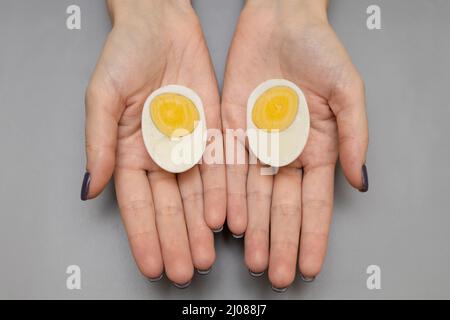 la moitié d'un œuf bouilli se trouve dans la paume d'une femme. Photo de haute qualité Banque D'Images