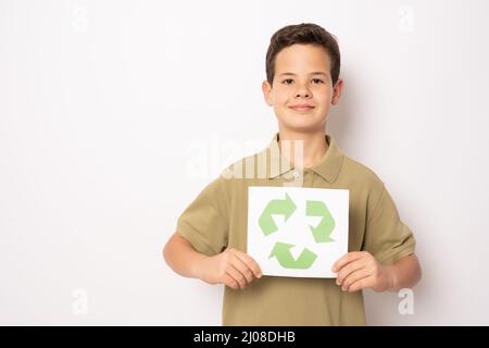 Petit garçon tenant le symbole de recyclage se tenant isolé sur fond blanc. Concept écologique. Banque D'Images