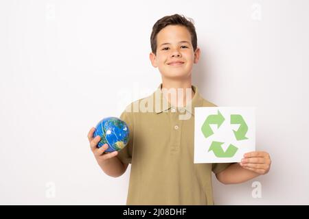 Petit garçon tenant le symbole de recyclage et le globe terrestre se tenant isolé sur fond blanc. Concept écologique. Banque D'Images