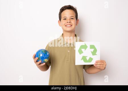 Petit garçon tenant le symbole de recyclage et le globe terrestre se tenant isolé sur fond blanc. Concept écologique. Banque D'Images