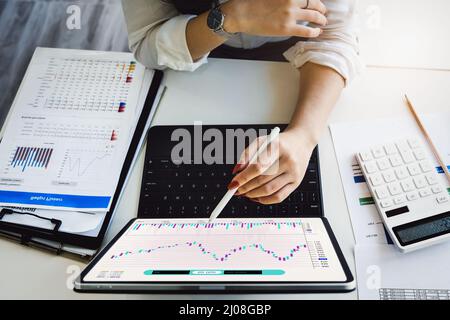 Idées de marché boursier, investissements, gestion de risque femme tenant un stylo pointant vers tablette étudiant le marché boursier de son budget prévu pour gérer le stock Banque D'Images