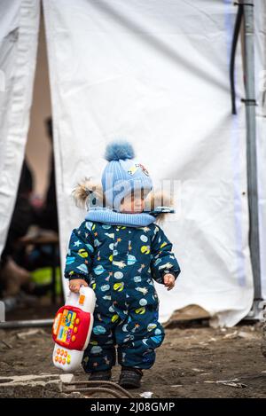 Tir vertical d'un garçon ukrainien debout avec d'autres réfugiés dans un camp de Medyka, en Pologne Banque D'Images