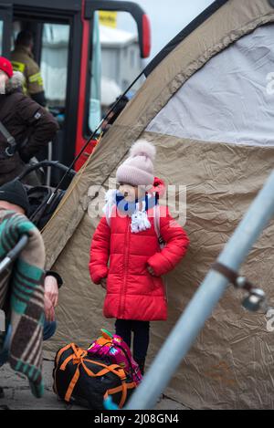 Plan vertical d'une fille ukrainienne debout contre une tente avec des réfugiés dans une gare routière en Pologne Banque D'Images
