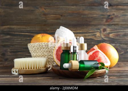 Composition avec bouteilles d'huile essentielle de pamplemousse et fournitures de bain sur fond de bois Banque D'Images