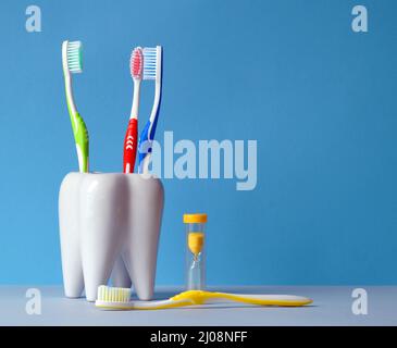 Les brosses à dents sont dans un verre, il y a un sablier à côté, pour compter le temps de se brosser les dents, et une brosse se trouve sur la table Banque D'Images