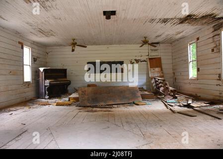 L'église de campagne est abandonnée et vide. Le piano antique, et orné, a été laissé pour se désintégrer. Le vieux pew en bois est cassé. Affiche imprimée à la main sur le Banque D'Images