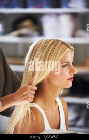 Préparation en coulisses. Jolie jeune femme coiffée par un styliste. Banque D'Images