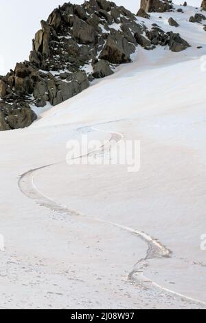 Piste de ski unique sur une pente intacte couverte de nuages de poussière de sable rouge soufflés du désert du Sahara par le vent de Foehn au début du printemps dans les Grands Montets A. Banque D'Images