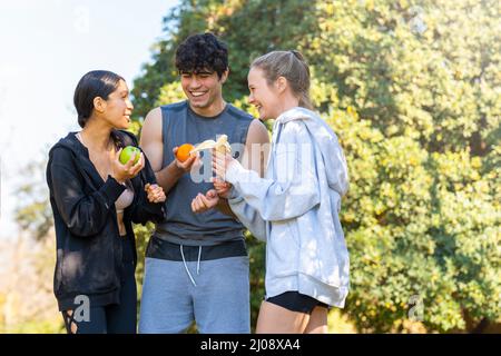 Les jeunes qui font du sport font une pause et mangent des fruits dans le parc Banque D'Images