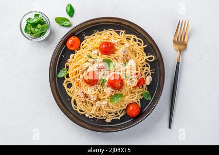 Fetapasta dans une plaque noire sur fond gris. Feta cuit avec tomates cerises. Vue de dessus. Banque D'Images
