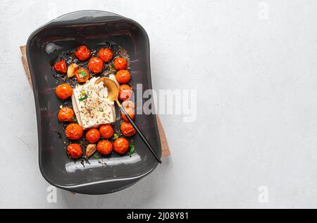 Fromage feta, tomates cerises et herbes cuites au four. Fetapasta sur fond gris. Banque D'Images