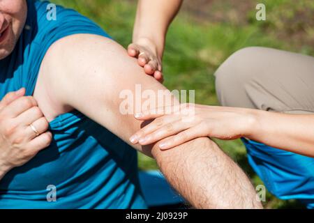 Un homme en randonnée a subi une blessure au coude ou à l'articulation de l'épaule et son partenaire fait un massage et fournit les premiers soins Banque D'Images