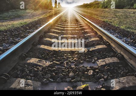 les rails se délochent à la distance contre l'arrière-plan du coucher du soleil Banque D'Images