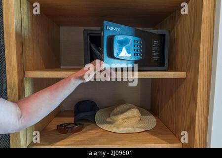 Vue rapprochée de l'homme ouvre la porte du coffre-fort qui se trouve sur une étagère dans le placard de la chambre d'hôtel. Grèce. NEA Potidaea. Banque D'Images