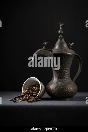 Ancienne cafetière arabe aux grains de café rôtis. Les grains de café débordent d'une tasse. Photo. Banque D'Images