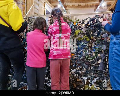 Les femmes et les enfants serpentent des filets de camouflage pour l'armée ukrainienne. Assistance volontaire aux forces armées de l'Ukraine. La guerre en Ukraine Banque D'Images