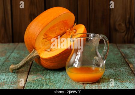 Jus de citrouille dans un pot en verre et couper la citrouille avec des graines sur une table en bois turquoise horizontale Banque D'Images