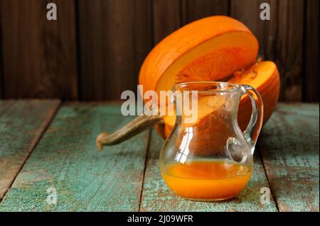 Jus de citrouille dans un pot en verre et couper la citrouille avec des graines sur la table en bois turquoise copyspace Banque D'Images