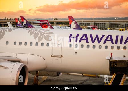 Vue sur les avions Hawaiian Airlines au coucher du soleil au terminal Interisland de l'aéroport international d'Honolulu, Oahu, Hawaii, États-Unis. Banque D'Images