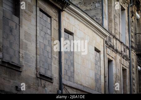 Flou sélectif sur les fenêtres condamnées, à bord et virées sur une façade de l'ancien immeuble résidentiel d'appartement dans une rue de la vieille ville, CEN historique Banque D'Images