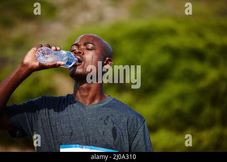 H2O - Un meilleur ami des coureurs. Photo d'un jeune homme qui boit de sa bouteille d'eau pendant une course. Banque D'Images