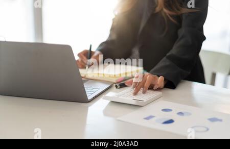 Gros plan comptable travaillant sur le bureau au bureau à l'aide de la calculatrice pour calculer le budget tout en prenant note sur le bloc-notes. Concept finance et comptabilité Banque D'Images