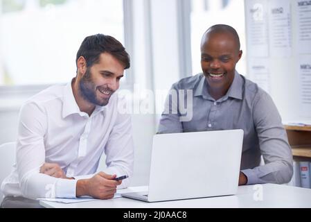 En travaillant sur leur nouveau plan d'affaires passionnant. Deux hommes d'affaires assis dans un bureau avec un ordinateur portable pendant une réunion. Banque D'Images
