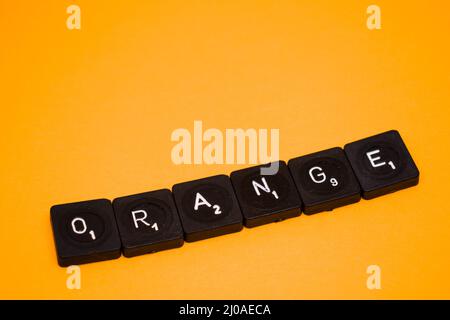 Gros plan des carreaux noirs scrabble indiquant le mot orange sur fond orange Banque D'Images