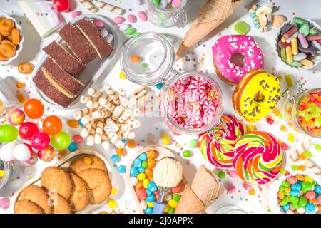 Sélection de bonbons colorés. Assortiment de bonbons, chocolats, beignets, biscuits, sucettes, vue de dessus de crème glacée sur fond blanc Banque D'Images