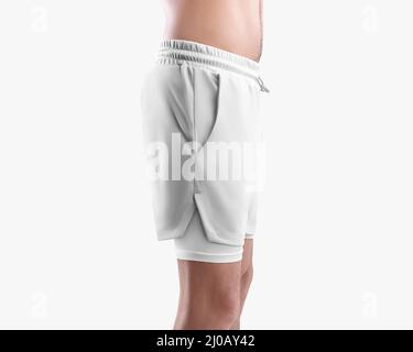 Maquette de short blanc ample pour homme avec doublure de compression, short d'entraînement sur le corps sportif d'un homme, isolé sur le fond. Modèles de vêtements de sport Banque D'Images