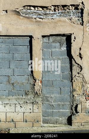 Vue détaillée d'un mur détérioré avec briques apparentes et plâtre en ruine dans un bâtiment abandonné Banque D'Images