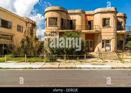 Le quartier de Varosha (Kapalı Maraş) à Famagouste (Chypre) était entre 1970 et 1974 l'une des destinations touristiques les plus populaires dans le monde. Ses habitants chypriotes grecs ont fui lors de l'invasion turque de Chypre en 1974, lorsque la ville de Famagouste est passée sous contrôle turc. Il est resté abandonné depuis et les bâtiments se sont dégradés. Une poignée de routes à l'intérieur de la station ont été refaites pour faciliter l'exploration. Il est même possible de louer un vélo une fois que vous passez par le poste de contrôle militaire - bien qu'il n'y ait que quelques rues ouvertes et que la zone soit assez petite pour marcher Ar Banque D'Images