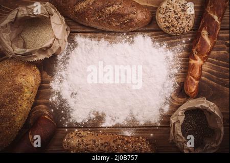 Différents types de pain sur table en bois saupoudrés de farine. Vue de dessus Banque D'Images