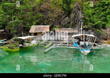 Deux bateaux en bois en face de Nipa maison en bois sur pilotis au bord de la mer Banque D'Images