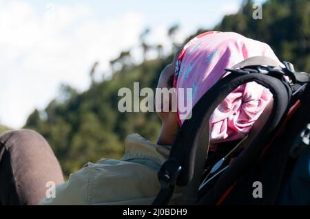 Jeune homme avec bandana rose pose repos sur son sac à dos dans le soleil dort Banque D'Images