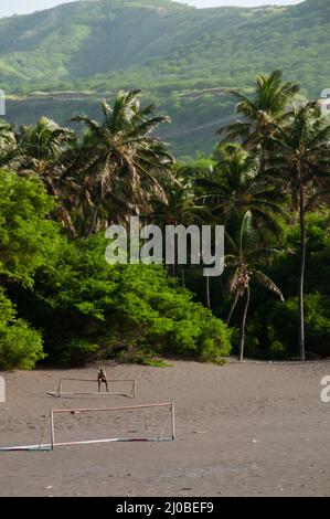 Deux buts de football sur plage de sable noir en face de palmiers Banque D'Images