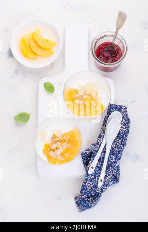 Compote de pêches et de poires sucrées avec yaourt dans un verre et confiture sur un tableau blanc. Vue du dessus Banque D'Images