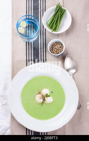 Soupe aux pois avec l'oignon de printemps et la mozzarella sur une table Banque D'Images