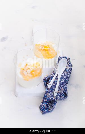 Compote de pêches et de poires sucrées avec yaourt dans un verre et confiture sur un tableau blanc Banque D'Images