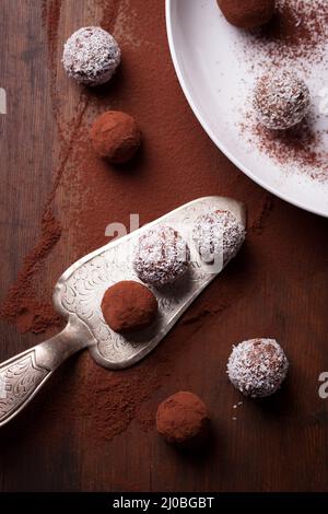 Bonbons de chocolat au cacao et de chips de noix de coco sur une plaque blanche, vue du dessus, selective focus Banque D'Images