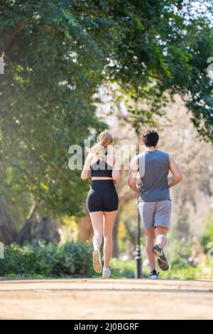 Vue arrière d'un jeune couple qui fait du sport sur un sentier de parc Banque D'Images