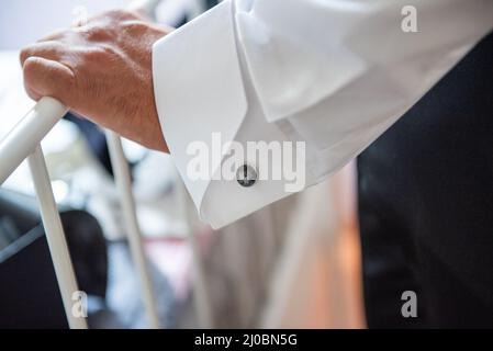 Mars 2022, la main de l'homme repose sur le fer d'un lit, un brassard de chemise et un lien de manchette Banque D'Images