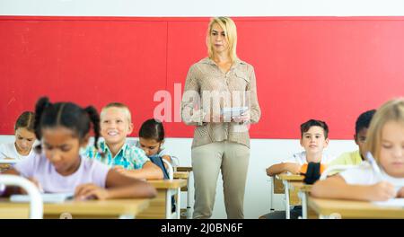 Femme enseignante aidant la préadolescence des écoliers pendant la leçon Banque D'Images
