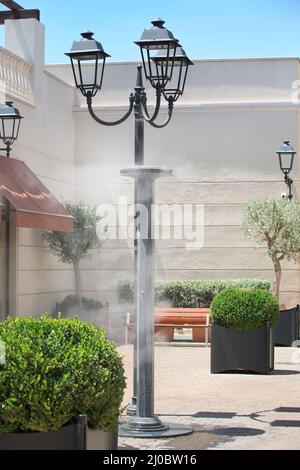 Les gicleurs éclaboussant de l'eau vaporisée dans la rue afin de refroidir la température estivale chaude Banque D'Images