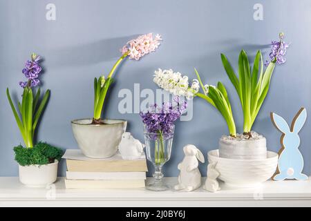 Jacinthe blanche dans un grand bol en porcelaine, figurines de lièvres et un oiseau, sont sur la cheminée contre le mur bleu foncé. Mise en page. Concept de ressort Banque D'Images