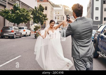 Faire de leur grand jour un jour mémorable. Photo d'un marié prenant une photo de sa mariée sur son téléphone portable. Banque D'Images