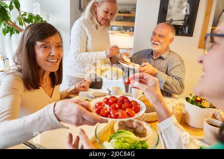 Groupe heureux d'aînés comme amis manger ensemble à la maison Banque D'Images