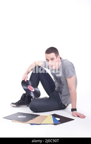 Un jeune homme assis sur le sol et passe en revue les disques en vinyle Banque D'Images