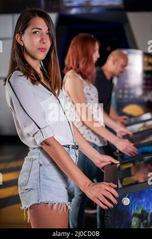 Les personnes qui jouent au flipper dans la salle de jeux vidéo Banque D'Images