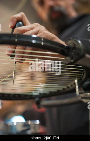Machine à élingage. Détail des mains de la stringer de tennis tout en tenant l'auge et en faisant la racket de raquette Banque D'Images